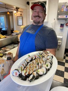 travis hickey with a plate of sushi rolls